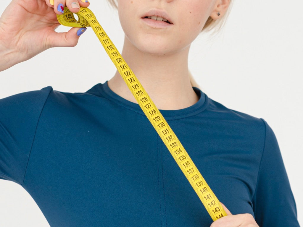 Woman in Blue Shirt with Tape Measure Diagonally Extended across Upper Body
