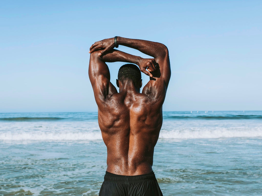 Muscular Man doing Tricep Stretch by the Ocean